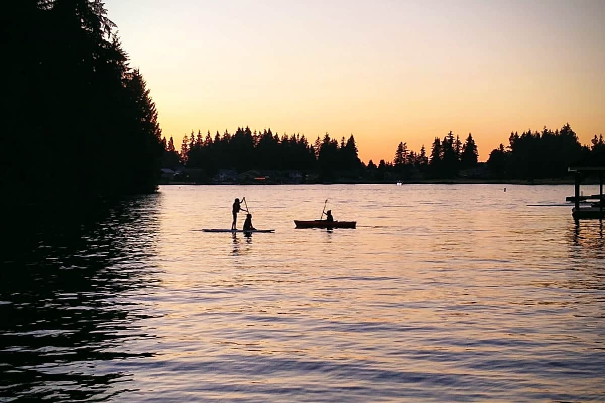 Silhouette picture of kids kayaking and paddle boarding.